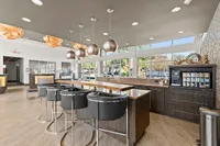 Luxurious modern lounge featuring sleek bar seating, stylish pendant lights, and panoramic windows with natural views.