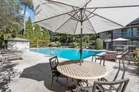 Inviting pool area with modern sun loungers, shaded seating, and lush greenery, perfect for relaxation and leisure.