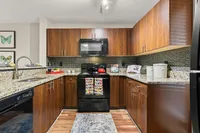 Modern kitchen with sleek wooden cabinetry, granite countertops, and stainless steel appliances, perfect for culinary enthusiasts.