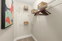 Sleek walk-in closet with modern shelving and tasteful wicker baskets, perfect for organized living.