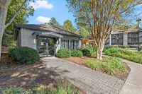 Charming residential building surrounded by lush greenery and a picturesque pathway, creating a serene and welcoming atmosphere.