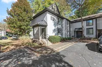 Charming townhouse with modern architecture, surrounded by lush greenery and ample parking space, set in a serene neighborhood.