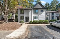 Charming apartment building with modern exterior, surrounded by lush greenery and ample parking space.
