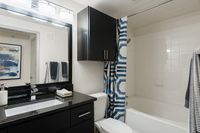 Modern bathroom featuring sleek black cabinetry, elegant lighting, and a stylish blue accent shower curtain.