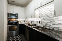 Modern kitchen with sleek stainless steel appliances, stylish mosaic tile backsplash, and dark granite countertops.
