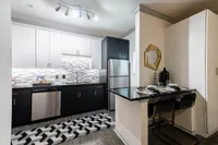 Modern kitchen with sleek black and white cabinetry, stylish mosaic backsplash, stainless steel appliances, and a cozy dining nook.
