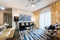 Chic living room with modern art, plush black sofa, and bold patterned decor, offering a blend of elegance and comfort.
