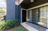 Chic apartment patio featuring modern metal chairs and a stylish geometric rug, offering a cozy outdoor relaxation space with lush greenery.