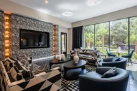 Chic and modern living room with large windows, elegant geometric furniture, and lush outdoor views.