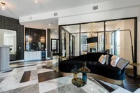 Sophisticated modern living space with sleek black and gold accents, elegant geometric lighting, and cozy seating area.