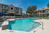 Charming apartment complex with a sparkling swimming pool, sun loungers, and lush greenery, perfect for relaxation and leisure.