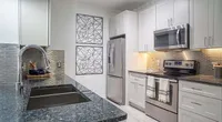 Modern kitchen with sleek stainless steel appliances, elegant white cabinetry, and a stylish granite countertop.