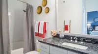 Contemporary bathroom with elegant granite countertop, modern fixtures, and vibrant red accents, offering a stylish touch.