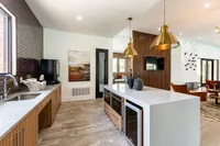 Luxurious modern kitchen and living area featuring sleek countertops, elegant pendant lighting, and chic decor accents.