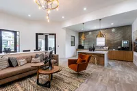 Sophisticated modern living room with elegant chandelier, cozy seating, and sleek kitchen island, exuding contemporary charm and style.