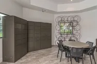 Modern communal room with round table, artistic wall decor, and sleek storage cabinets, exuding a contemporary vibe.