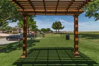 Charming outdoor space featuring a wooden pergola, lush green lawns, and serene surroundings perfect for relaxation.