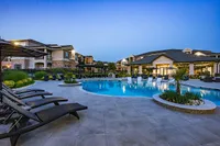 Luxurious apartment complex featuring a serene pool area with sun loungers and lush greenery, perfect for relaxation and enjoyment.