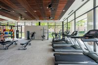 Bright and modern fitness center with large windows, featuring state-of-the-art treadmills, workout benches, and colorful exercise equipment.