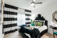 Chic bedroom with elegant decor, featuring a plush velvet bed, stylish black-and-white curtains, and modern accessories.