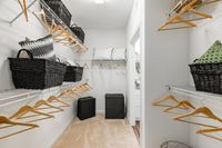 Spacious and well-organized walk-in closet featuring abundant shelving, stylish black baskets, and elegant wooden hangers, perfect for wardrobe organization.