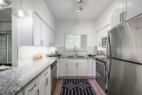 Modern kitchen with sleek white cabinetry, stainless steel appliances, granite countertops, and elegant lighting.