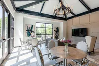 Elegant shared living area with high ceilings, modern chandelier, stylish seating, and large windows offering natural light.