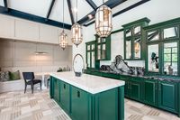 Elegant kitchen with striking green cabinets, luxurious marble countertops, and stylish pendant lighting.