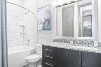 Elegant bathroom featuring a marble-tiled shower, modern vanity with granite countertop, and stylish decor.