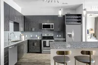 Modern kitchen with sleek dark cabinets, stainless steel appliances, and elegant pendant lighting over a granite breakfast bar.