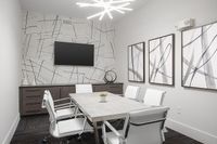 Modern conference room with chic geometric decor, sleek table, and stylish white chairs under contemporary lighting.