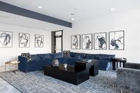 Sophisticated living room with plush navy sectional, modern art pieces, and contemporary black coffee table.