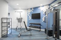 Modern apartment gym with state-of-the-art equipment, blue accent wall, and sleek design, perfect for fitness enthusiasts.