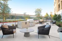 Chic outdoor patio with modern seating, a sleek barbecue grill, and lush greenery for an inviting atmosphere.