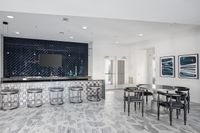 Modern communal dining area featuring a sleek black and silver design with a chic tiled bar and contemporary artwork.