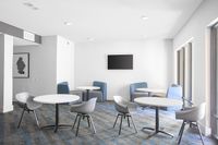 Bright and modern communal lounge area with sleek tables, ergonomic chairs, and large windows for natural light.