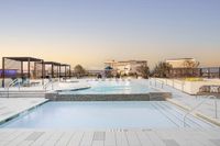Luxurious rooftop pool with chic cabanas and a stunning cityscape view at sunset, perfect for relaxation and leisure.
