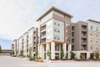 Modern apartment building with sleek architecture, large windows, and a welcoming entrance at The Cue Apartments.