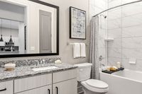 Elegant bathroom with chic granite countertop, modern fixtures, and a stylish bathtub featuring a marble-patterned tile surround.
