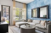 Chic living room with elegant decor, featuring a plush sectional sofa, stylish round coffee table, and a serene blue accent wall with modern mirrors.