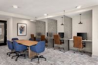 Modern co-working space with stylish meeting table and individual workstations, featuring chic decor and ambient lighting.