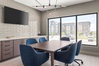 Modern apartment meeting room with sleek furniture, large window view, and elegant light fixture.