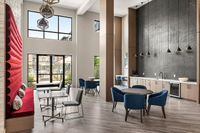 Chic modern apartment lounge with high ceilings, stylish blue seating, and an elegant kitchenette.