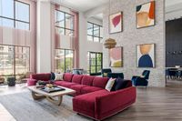 Elegant modern living room with a vibrant red sectional sofa, stylish wall art, and floor-to-ceiling windows offering abundant natural light.