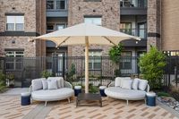 Chic outdoor patio space with cozy round seating, elegant umbrella, and modern building backdrop.