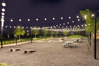 Charming outdoor space illuminated by strings of glowing lights, featuring picnic tables and inviting greenery, perfect for evening gatherings.