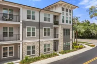 Apartment exterior with brick, tan siding and white siding in the day time