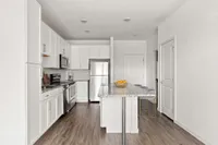 Furnished Kitchen with kitchen island, white cabinets, and stainless steel appliances