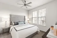 Furnished bedroom with lighted ceiling fan, two windows and bedside tables with lamps