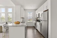 Furnished kitchen with large counter, sink, white cabinets, and stainless steel appliances
